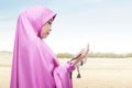 Asian Muslim woman in veil praying with prayer beads on her hands Royalty Free Stock Photo