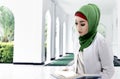 Asian Muslim woman in a veil sitting and reading the Quran Royalty Free Stock Photo