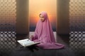 Asian Muslim woman in a veil sitting and reading the Quran Royalty Free Stock Photo