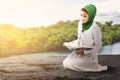 Asian Muslim woman in a veil sitting and reading the Quran Royalty Free Stock Photo