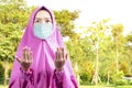 Asian Muslim woman in a veil and wearing flu mask standing while raised hands and praying Royalty Free Stock Photo