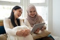 An Asian-Muslim woman is watching videos or a movie on a tablet with her friend in a room together Royalty Free Stock Photo