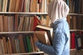 Asian muslim woman wearing hijab picking book in bookshelf, education concept, reading learning studying in library Royalty Free Stock Photo