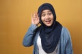 Asian muslim woman wearing hijab smiling while doing hearing gesture, shocked surprised expression to hear gossip Royalty Free Stock Photo