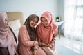 Asian muslimah woman enjoy chatting while sitting on the bed