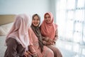 Asian muslimah woman enjoy chatting while sitting on the bed