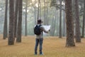 Asian naturalist looking at the map for direction while exploring wildlife in the pine forest for surveying and discovering the Royalty Free Stock Photo