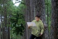 Asian naturalist looking at the map for direction while exploring wildlife in the pine forest for surveying and discovering the Royalty Free Stock Photo