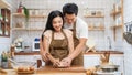 Asian new marriage couple stay home, spend time together in kitchen. Romance Young attractive husband and wife enjoy kneaded yeast