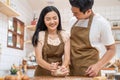 Asian new marriage couple stay home, spend time together in kitchen. Romance Young attractive husband and wife enjoy kneaded yeast