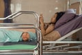 Baby laying in crib with his mother using mobile phone laying on bed side Royalty Free Stock Photo