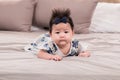 Asian newborn baby 3 month wearing a cute blue floral dress and a headband with bow lying prone on beige soft bed. healthy Royalty Free Stock Photo