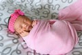 Asian newborn baby sleepin in pink cloth wearing headband