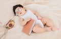 Asian Newborn baby wearing glasses with favorite book on beige blanket , 3 month-old infant lying in bed with relax. Adorable baby Royalty Free Stock Photo