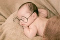 Asian Newborn baby wearing glasses and sleep on brown bed at home, 0-1month-old infant lying in blanket with relax. Adorable baby Royalty Free Stock Photo