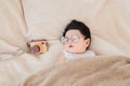 Asian Newborn baby wearing glasses sleeping with beige blanket next to toy camera with safe and comfortable. Adorable baby resting