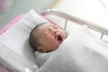 Asian newborn baby yawn in bassinet at delivery room at hospital