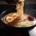 Asian noodle soup, ramen with chicken, vegetables and egg in a black bowl. on the table, side view Royalty Free Stock Photo