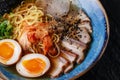 Asian noodle soup, ramen with pork, tofu, kimchi, vegetables and egg in blue bowl. Slate background. Top view. Bowl of Royalty Free Stock Photo