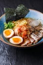 Asian noodle soup, ramen with pork, tofu, kimchi, vegetables and egg in blue bowl. Slate background. Top view. Bowl of Royalty Free Stock Photo