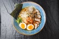 Asian noodle soup, ramen with pork, tofu, kimchi, vegetables and egg in blue bowl. Slate background. Top view. Bowl of Royalty Free Stock Photo