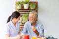 Asian nurse enjoy assist senior man having breakfast and happy together