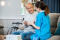 Asian nurse with physician explaining prescription medicine to attentive senior man at home Royalty Free Stock Photo