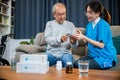 Asian nurse with physician explaining prescription medicine to attentive senior man at home Royalty Free Stock Photo