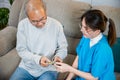 Asian nurse with physician explaining prescription medicine to attentive senior man at home Royalty Free Stock Photo