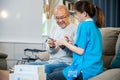 Asian nurse with physician explaining prescription medicine to attentive senior man at home Royalty Free Stock Photo