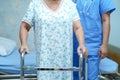 Asian nurse physiotherapist doctor care, help and support senior or elderly old lady woman patient walk with walker. Royalty Free Stock Photo