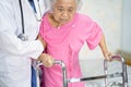 Asian nurse physiotherapist doctor care, help and support senior or elderly old lady woman patient walk with walker at hospital Royalty Free Stock Photo
