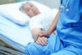 Asian nurse physiotherapist doctor care, help and support senior or elderly old lady woman patient lie down in bed at hospital war Royalty Free Stock Photo