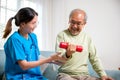 Asian nurse physiotherapist helping senior man in lifting dumbell at retirement home Royalty Free Stock Photo