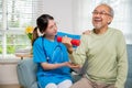 Asian nurse physiotherapist helping senior man in lifting dumbell at retirement home Royalty Free Stock Photo