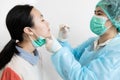 Asian nurse in protective suite taking a swab for nasal mucus test sample from child girl patient,medical examination COVID-19 Royalty Free Stock Photo