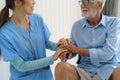 Asian nurse sitting on a hospital bed next to an older man helping hands, care. Elderly patient care and health lifestyle, medical Royalty Free Stock Photo