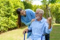 Asian nurse sitting on a hospital bed next to an older man helping hands care in garden at home. Elderly patient care and health Royalty Free Stock Photo