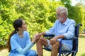 Asian nurse sitting on a hospital bed next to an older man helping hands care in garden at home. Elderly patient care and health Royalty Free Stock Photo