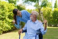 Asian nurse sitting on a hospital bed next to an older man helping hands care in garden at home. Elderly patient care and health Royalty Free Stock Photo