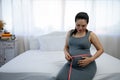 Asian obese pregnant woman in a grey dress with big belly measuring baby bump with tapeline Royalty Free Stock Photo