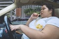 Asian obese woman eating during driving a car