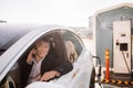 Asian office worker chatting on cell and charging e-car Royalty Free Stock Photo