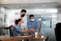 Asian office workers wearing face masks working in new normal office and doing social distancing