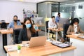 Asian office workers wearing face masks working in new normal office and doing social distancing