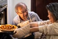 Asian old grandparents making pizza at home. Aged woman open the oven and bring the food out from machine. Elder man looking at me Royalty Free Stock Photo