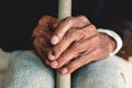 Asian old man sitting with his hands on a walking stick Royalty Free Stock Photo