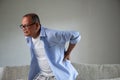 Asian old man sitting on sofa and having a back pain, backache at home. Senior healthcare concept Royalty Free Stock Photo