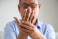 Asian old man sitting on sofa and having hand pain, hand injury at home. Senior healthcare concept Royalty Free Stock Photo