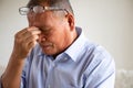 Asian old man sitting on sofa and having a headache at home. Senior healthcare concept Royalty Free Stock Photo